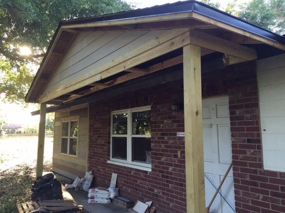 New covered porch roof with wood posts and a dark metal edge on a brick home