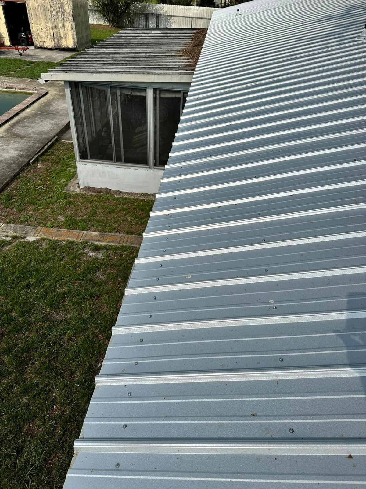 Metal roof panels running down to the eave next to a screened porch